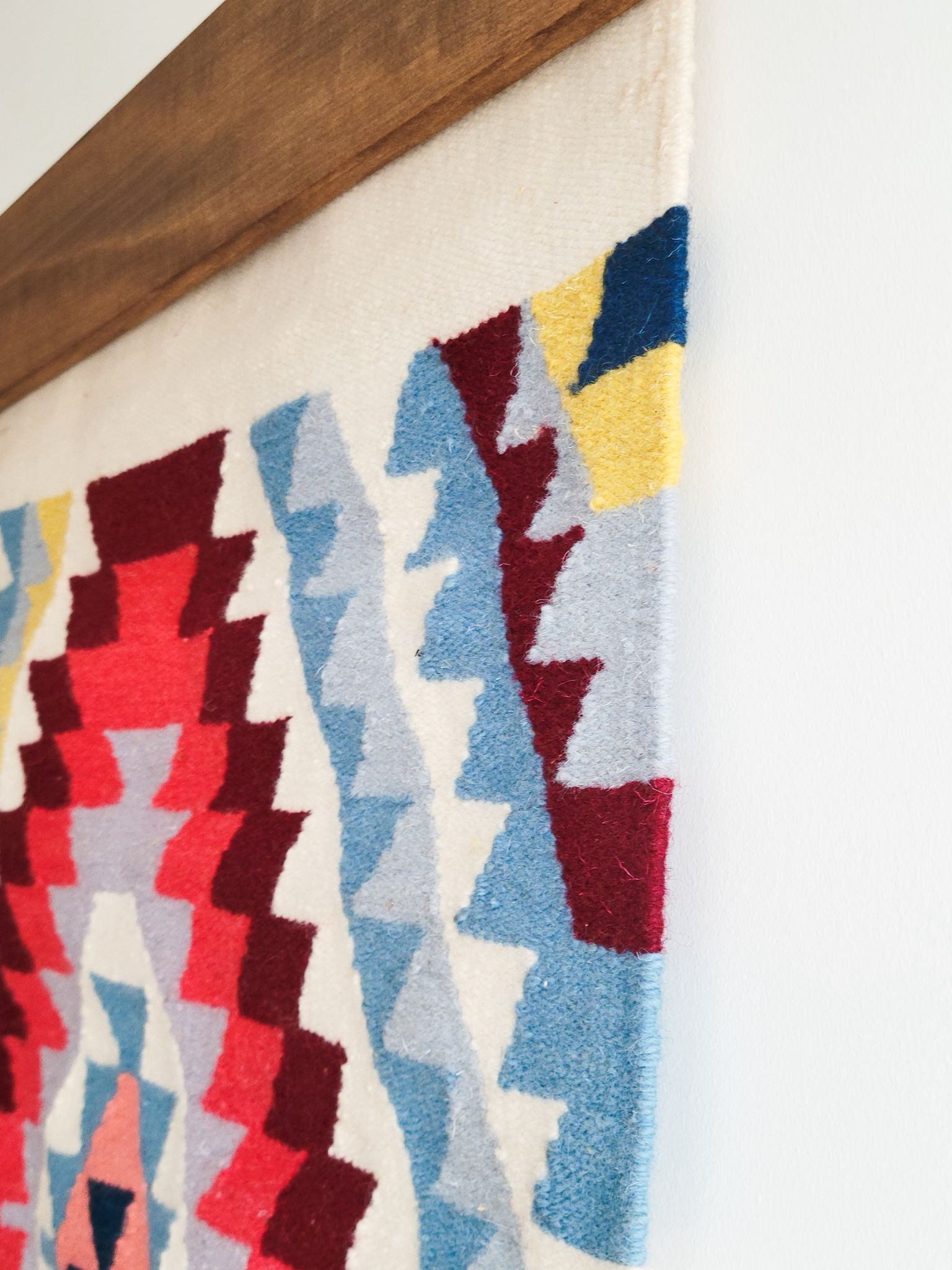 Close-up of a colorful geometric patterned rug with a wooden border.