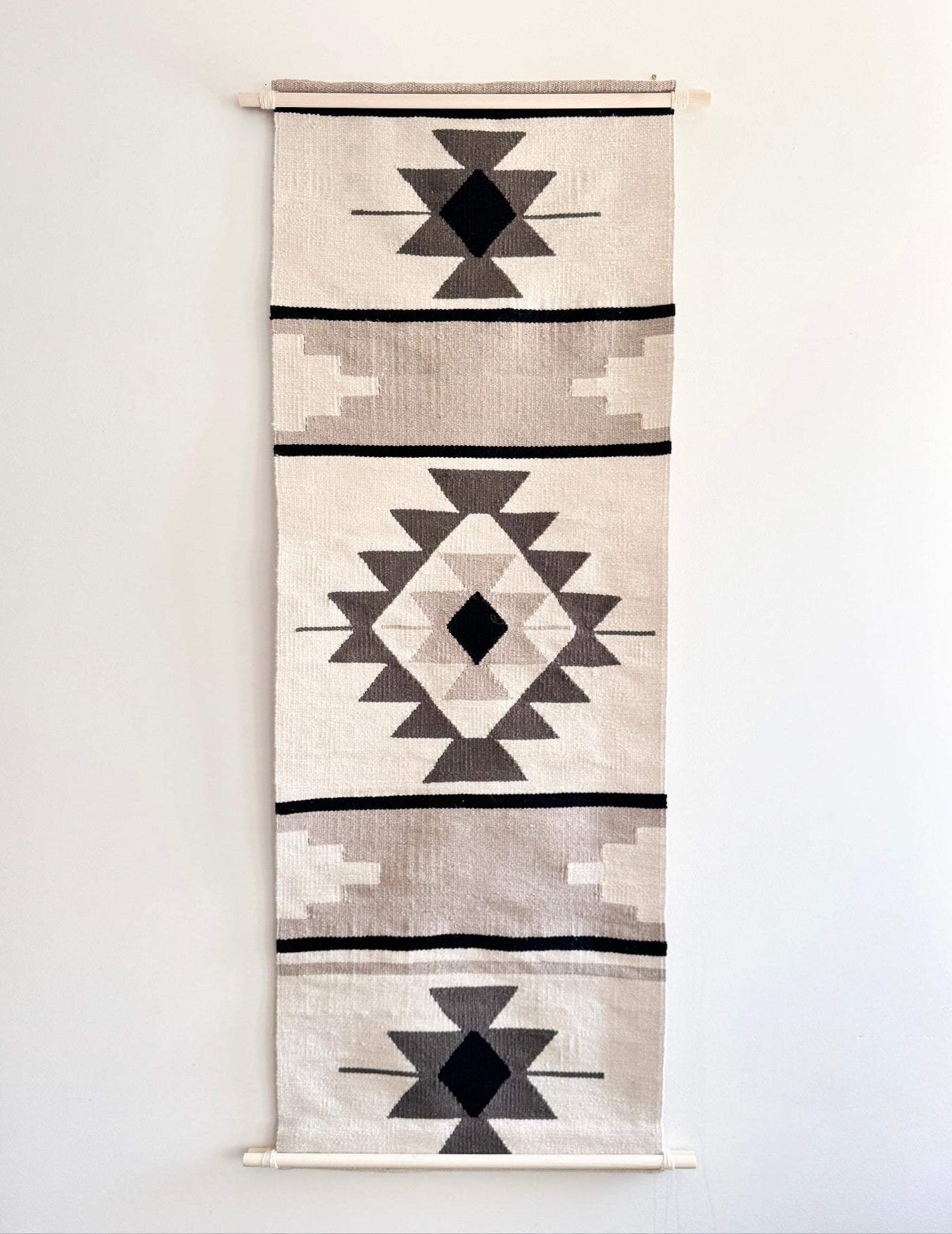 Woven wall hanging with geometric pattern on a plain background