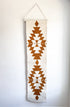 Decorative wall hanging with geometric pattern on a plain background
