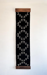 Vertical black banner with white geometric pattern and wooden frame on a light background