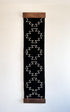 Vertical black banner with white geometric pattern and wooden frame on a light background