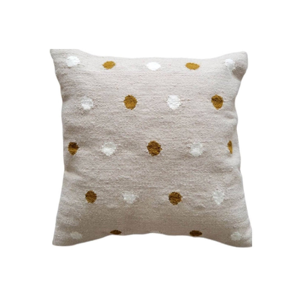 Decorative pillow with gold and white polka dot pattern on a beige background