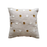 Decorative pillow with gold and white polka dot pattern on a beige background