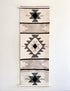 Woven wall hanging with geometric pattern on a plain background