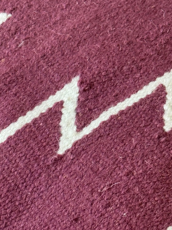 Close-up of a textured mulberry pillow with white geometric pattern