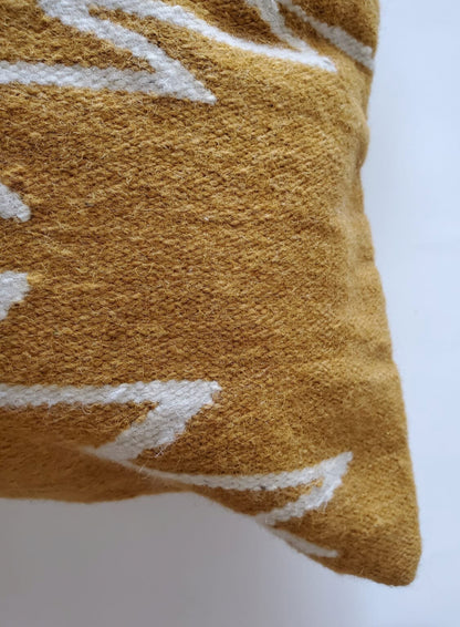 Close-up of a textured mustard yellow pillow with white patterns on a white background