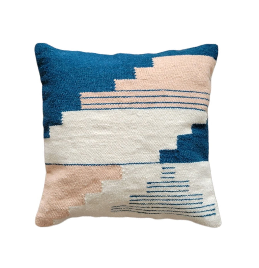 Decorative pillow with geometric pattern in blue, pink, and white on a white background