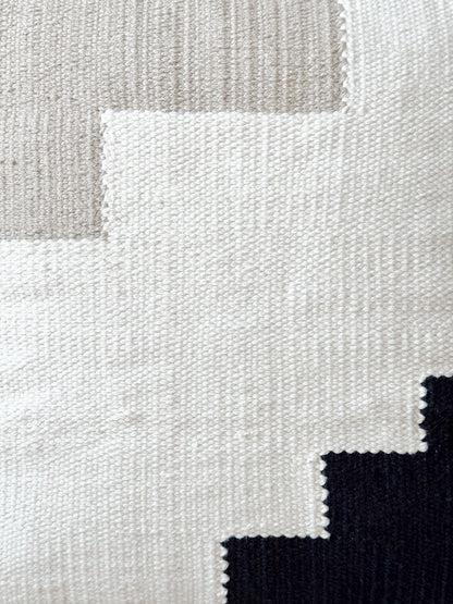 Close-up of a textured fabric with geometric pattern in beige, white, and black.
