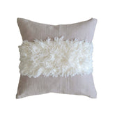 Decorative pillow with white fluffy top and taupe back on a white background