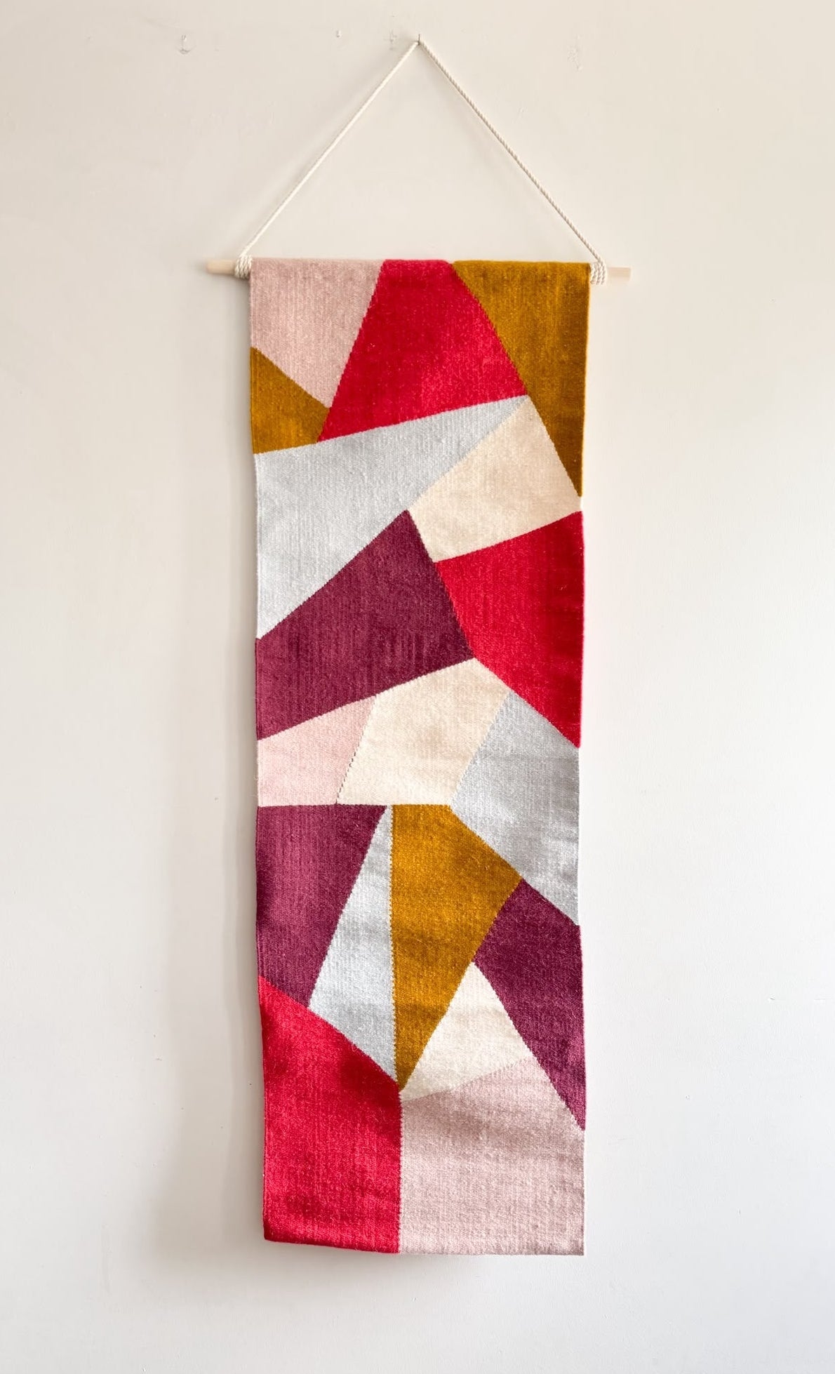 Colorful geometric patterned tapestry hanging on a white wall